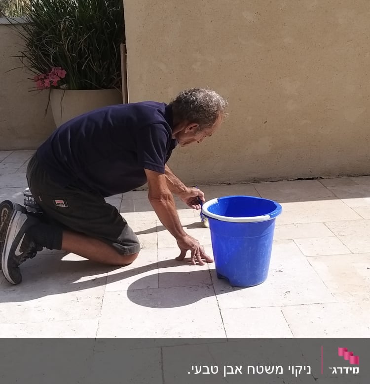 אדם מנקה רצפה עם דלי ומברשת